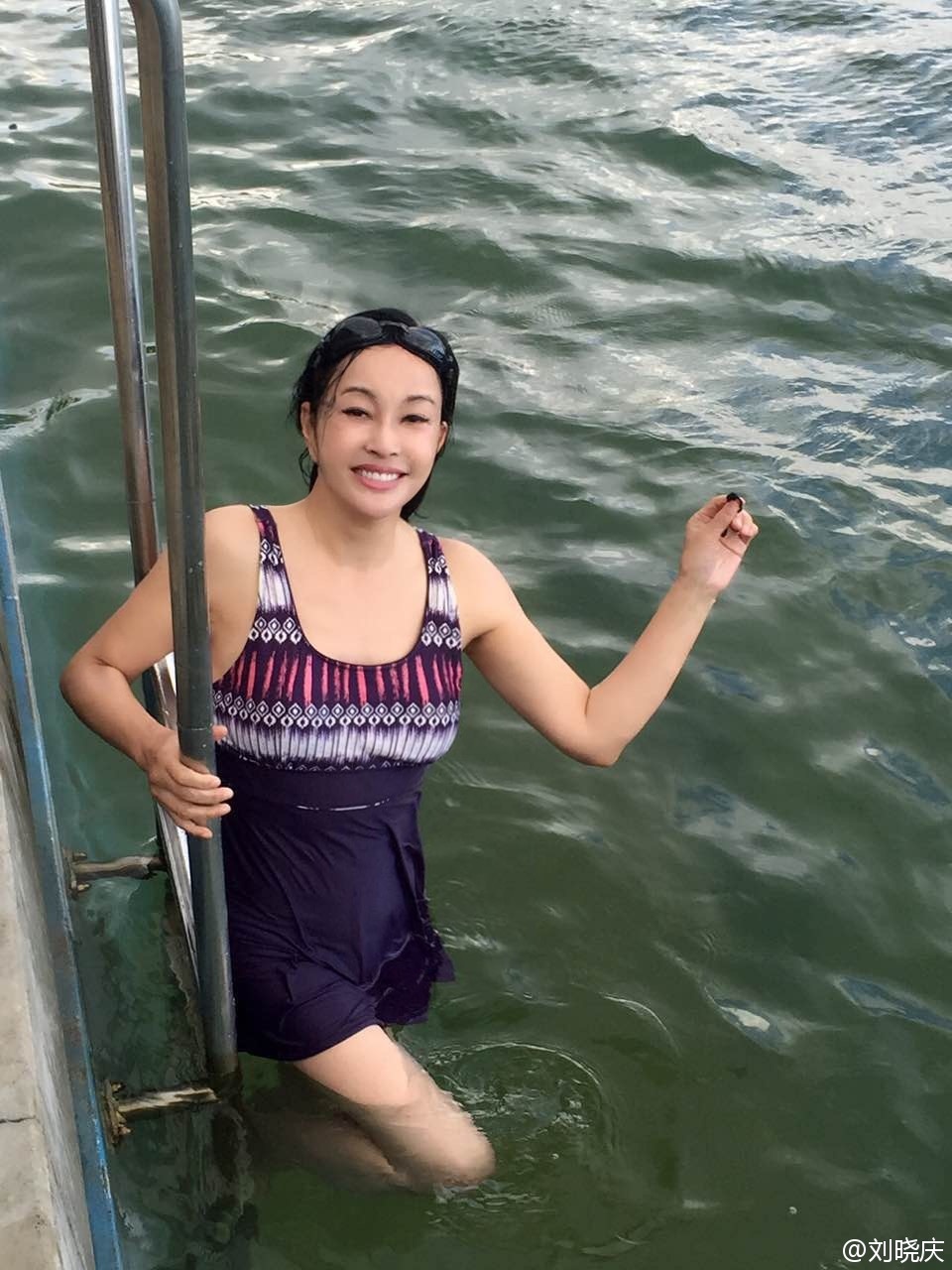 刘晓庆 照片中,刘晓庆湿身浸在水中,头发垂在脸颊两侧,尽管泳衣为保守